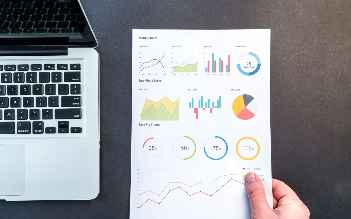 A laptop and printed reports showing website traffic charts and analytics data.