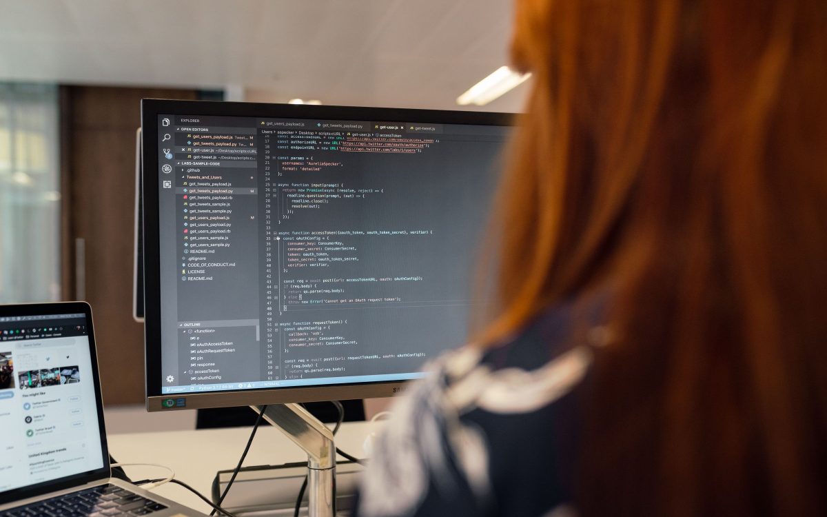 A developer working at a desk with code on a large monitor.